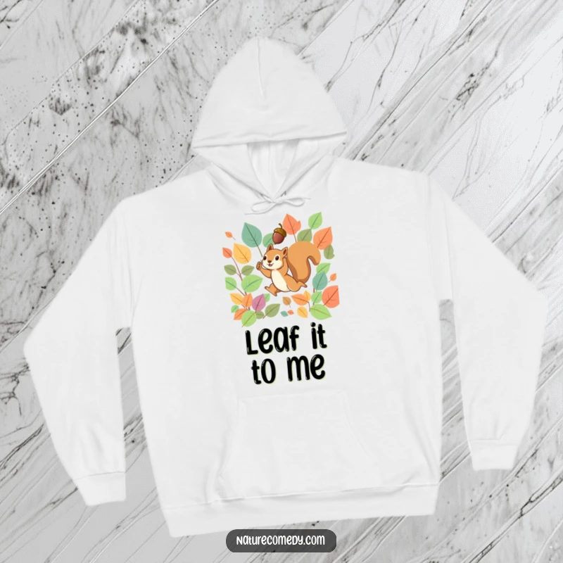 Funny hoodie showing a tiny squirrel leaping energetically through vibrant fall leaves, proudly holding a small acorn aloft.